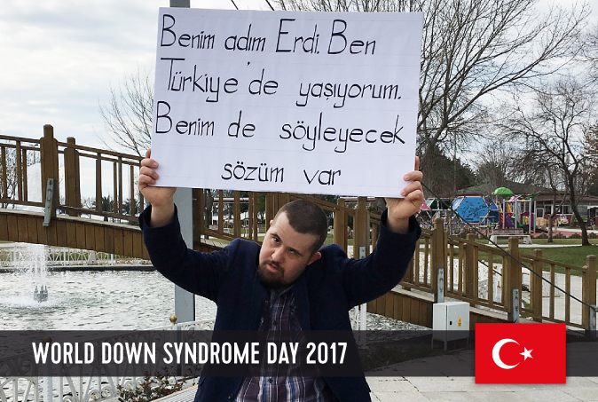 Young Turkish man with DS holding a sign with his statement on WDSD 2017 above his head