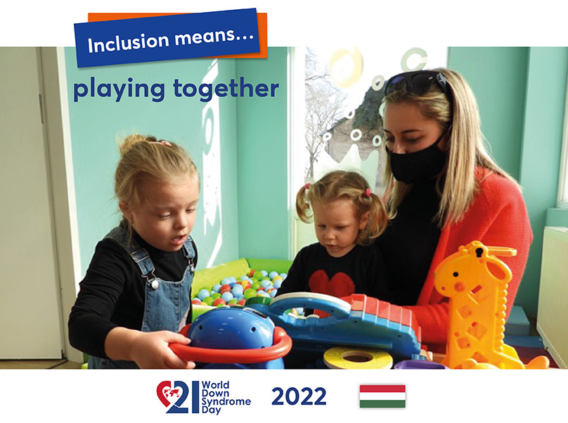 A mother together with her two little daughters (one of whom has Down syndrome) in a play corner playing with colourful toys.