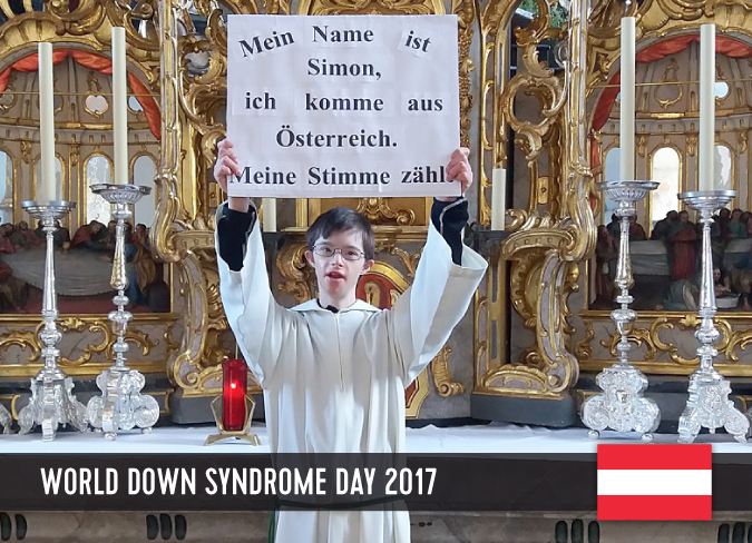 Young man with Down syndrome in a church, holding up a board with his statement.