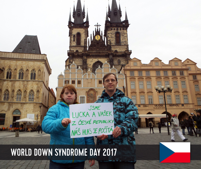 Young couple with Down syndrome on the old town square in Prague holding up a sign with their statement.