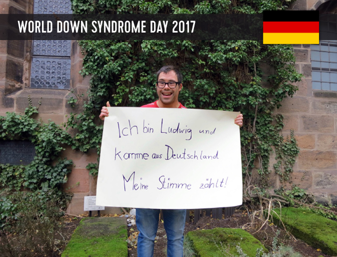 Young male from Germany with Down syndrome holding up a sign with his statement.