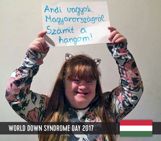 Young woman with Down syndrome holding a sign above her head with her statement to WDSD 2017.