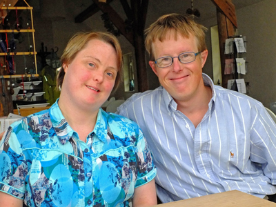 Young woman and young man with Down syndrome smiling at the camera.