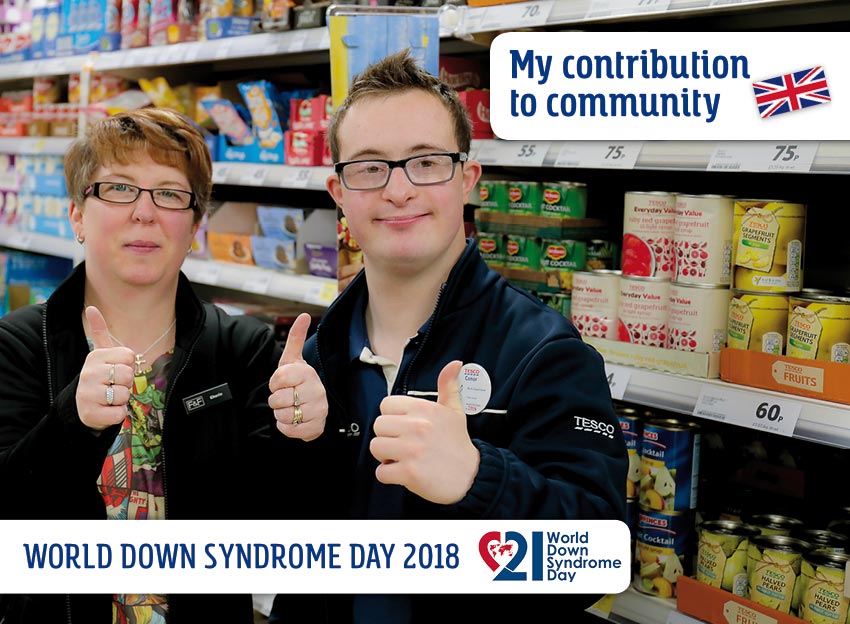 Conor (with DS) and his colleague stand in front of a food shelf in the supermarket. They look at the camera and show the gesture thumbs up.
