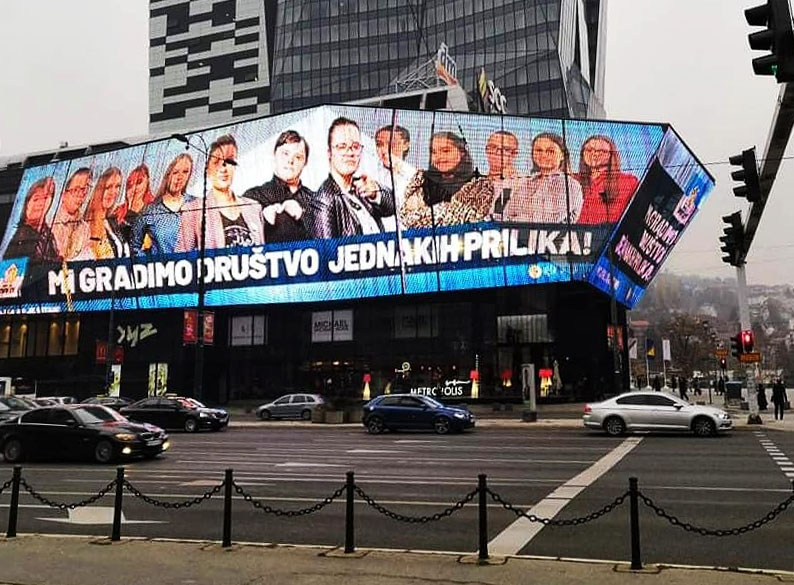 Big banner with a (fictitious) election advertisement featuring candidates with Down's syndrome as an eye-catcher on a commercial building. The Motto is: We build a society of equal opportunities!