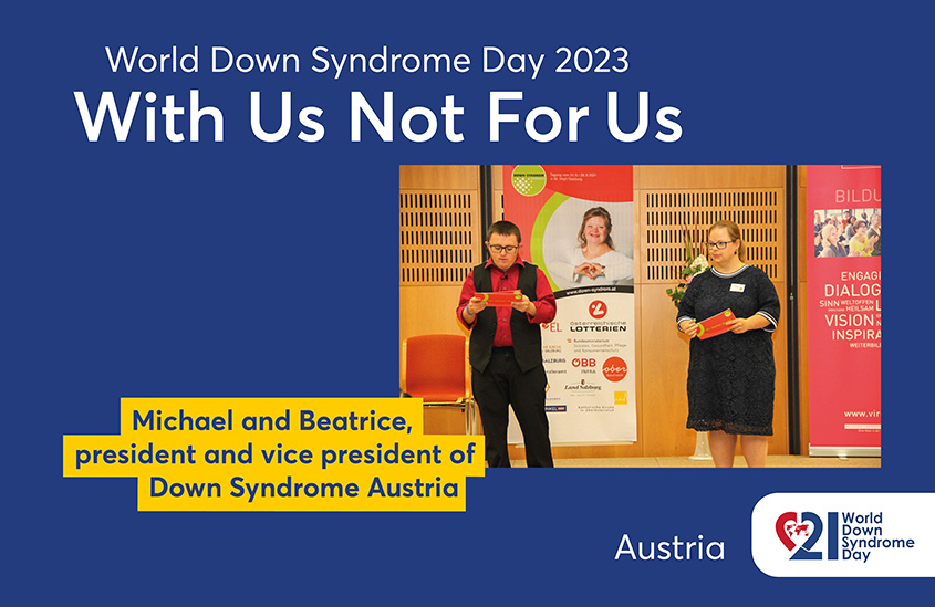 Poster of the 2023 EDSA WDSD Poster campaign “With Us Not For Us”. The photo shows Michael and his colleague Beatrice moderating the opening ceremony of a congress. Text to the photo shown: Michael and Beatrice, president and vice president of Down Syndrome Austria.