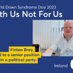 Poster of the 2023 EDSA WDSD Poster campaign “With Us Not For Us”. The photo shows Fintan Bray in a white shirt sitting at his desk. Text to the photo shown: Fintan Bray, elected to a senior position within a political party.